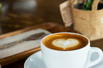 Hot coffee in a cup with foam milk beautiful art on wooden table background. Cappuccino or latte with froth foam, drinks concept.