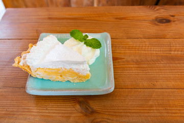 Selective focus of coconut cake on wooden table in cafe restaurant. Homemade Coconut cake. Coconut cake on plate on wooden table.