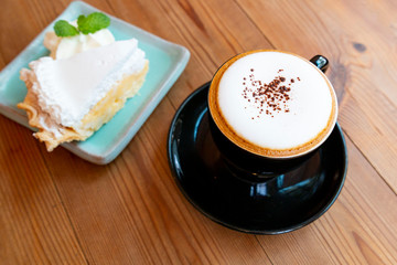 Cup of hot latte art cappuccino on wooden table. Hot coffee cup on table, relax time. Cup of cappuccino coffee on wooden table. Fresh brewed coffees with beautiful latte art on surface.