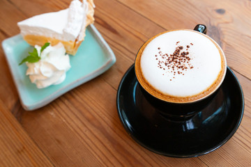 Cup of hot latte art cappuccino on wooden table. Hot coffee cup on table, relax time. Cup of cappuccino coffee on wooden table. Fresh brewed coffees with beautiful latte art on surface.