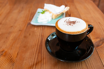 Cup of hot latte art cappuccino on wooden table. Hot coffee cup on table, relax time. Cup of cappuccino coffee on wooden table. Fresh brewed coffees with beautiful latte art on surface.