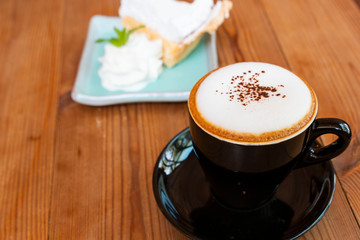 Cup of hot latte art cappuccino on wooden table. Hot coffee cup on table, relax time. Cup of cappuccino coffee on wooden table. Fresh brewed coffees with beautiful latte art on surface.