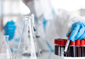 scientists in personal protective equipment or ppe doing research and experiment to find drugs to treat covid-19 or coronavirus infection in the lab