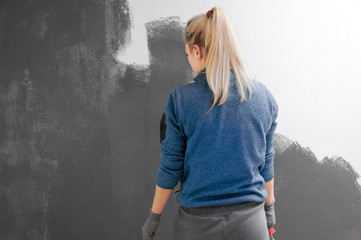 Girl holds a roller in hand close-up. Girl repaints the wall in gray. Repair in the room. DIY repair.