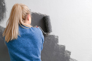 Girl holds a roller in hand close-up. Girl repaints the wall in gray. Repair in the room. DIY repair.