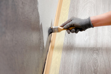 Girl repaints the wall in gray. Repair in the room. DIY repair.