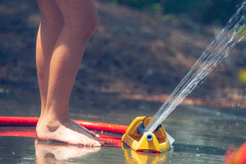 Low view kids feet in water sprinkler, summer fun, beat the heat, quarantine activity 