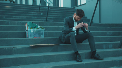 Man wear mask sitting on stairs head off with box of personal stuff and poster with the inscription Crisis 2020 got fired due to coronavirus crisis unemployed depression employment economy slow motion