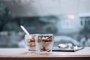 Tasty diet breakfast. Dessert in glasses on a white table. Bright and comfortable interior. Granola in a cup with blueberries and raspberries.