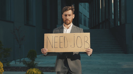 Portrait young businessman holding poster cardboard with Need Job jobless message sign coronavirus crisis text job showing professional finance economy slow motion