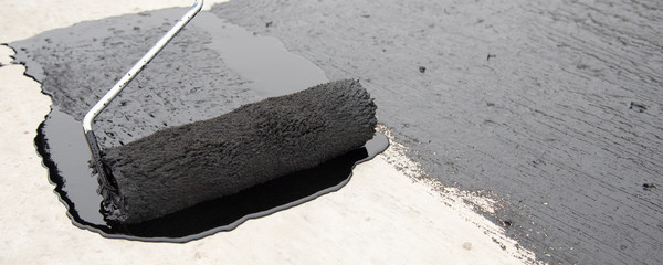 Worker applies bitumen mastic on the foundation