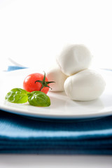 buffalo mozzarella from Campania and tomato with basil on a white background and placed on a blue napkin