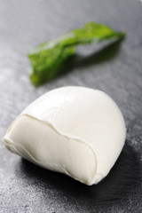 buffalo mozzarella and fried basil made by a chef with a very elegant design on black dish
