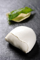 buffalo mozzarella and fried basil made by a chef with a very elegant design on black dish