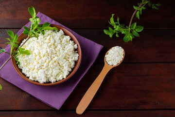 Cottage cheese on wooden boards. Fresh cottage cheese in a ceramic bowl. Soft cheese and wooden spoon on a linen napkin. Top view. Copy space