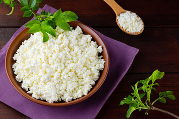 Cottage cheese on wooden boards. Fresh cottage cheese in a ceramic bowl. Soft cheese and wooden spoon on a linen napkin. Top view. Copy space