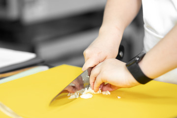 Obraz na płótnie Canvas Hands woman chef cut knife with garlic and onion on cutting board closeup