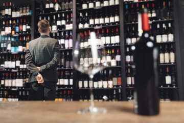 Sommelier Bartender choose wine bottle near rack store restaurant drinks