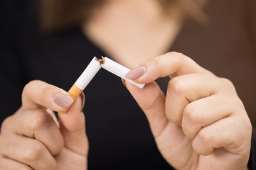 Close-up of a person holding a cigarette in their hand.