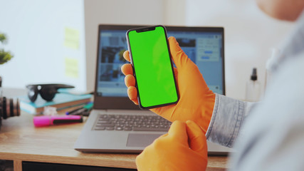 NEW YORK - March, 28, 2020: Young adult businessman using a smartphone tapping on vertical chroma...