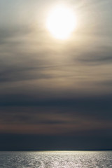 Fototapeta premium Sunset over the ocean with soft clouds under the sun