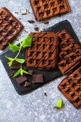 Homemade brownie waffles. Chocolate Belgian waffles with chocolate topping on a stone or slate table. Top view flat lay background. Copy space.