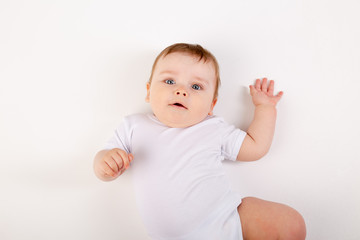 portrait of a cute baby boy with blue eyes in a white bodysuit against a white background, space for text