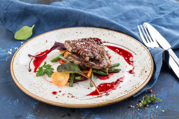 sirloin steak with green beans on white plate on blue background