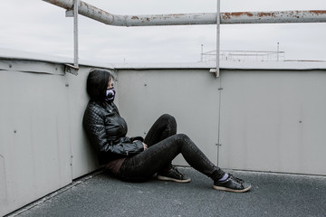 Sad girl in a mask sits on the roof