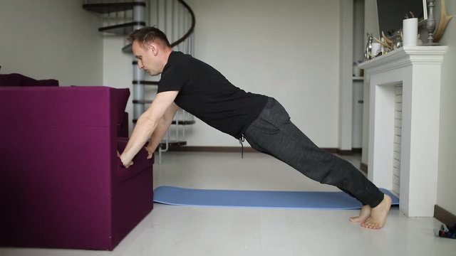 A young fit man does push-ups in his living room at home. Sport and healthy lifestyle