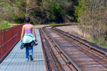woman walking over railroad bridge