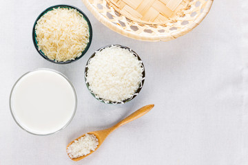 Rice milk on a white background. Rice milk in glass and rice seeds. Vegan non-dairy milk on a linen fabric. Alternative milk from rise. Minimalism. Copy space