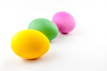 Obraz na płótnie Canvas Three easter eggs, green, violet or pink and orange or yellow, isolated on white background, colored by easter bunny