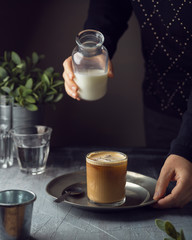 Cold coffee drink with milk over dark background