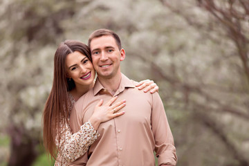 Fototapeta premium A happy family. Portrait of young parents awaiting baby in spring on nature in the park.