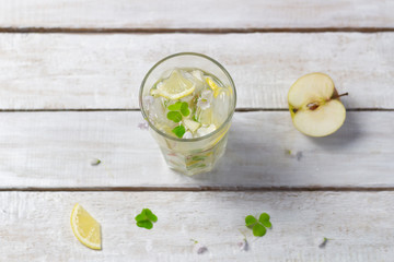 Flat lay on Lemonade with apple, lemon, wood sorrel, sugar, ice, water in high glass on white background