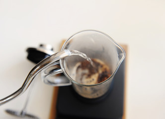 Brewing coffee in french press. Pouring hot water close up. Top view. White background