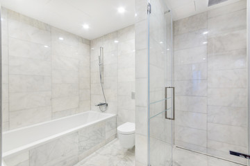 Fototapeta na wymiar Simple bathroom interior with bathtub, shower, and marble walls