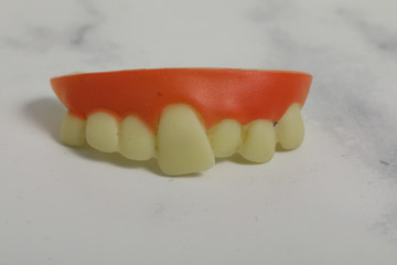 plastic monster teeth on white marble background