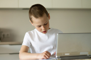 Boy 6-10 completes school lessons and homework online in the kitchen, looking at the tablet computer. The concept of distance education. Stay at home.