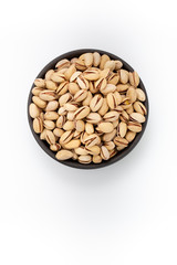 Roasted salty Pistachios  in round bowl on white background, top view