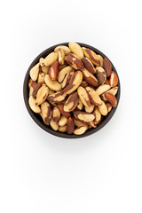 Brazil nuts in round bowl on white background, top view