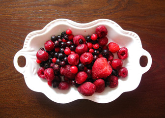 a mixture of frozen berries (black and red currants, cherries, strawberries) on a white plate