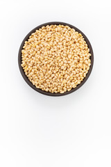 Cleaned Cedar nuts in round bowl on white background, top view