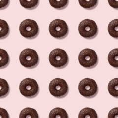 Colorful seamless pattern with glazed chocolate donuts. Pink pastel background. Confectionery banner.