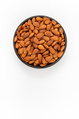 Raw Almonds nuts in round bowl on white background, top view