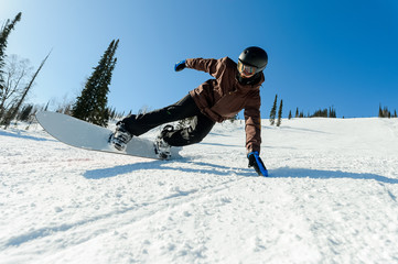 Young man carve the slopes with his snowboard. Snowboarder is making the trick on the slope.