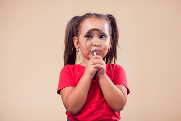 Fototapeta premium A portrait of kid girl holding magnifying glass. Childhood and education concept