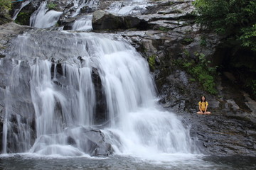 Fototapeta premium Woman sitting at Khlong Nam Lai waterfall in Klong Lan national park, Kamphaeng Phet, Thailand