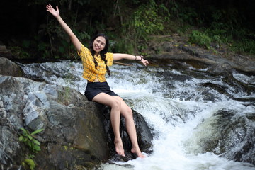 Woman sitting at Khlong Nam Lai waterfall in Klong Lan national park, Kamphaeng Phet, Thailand